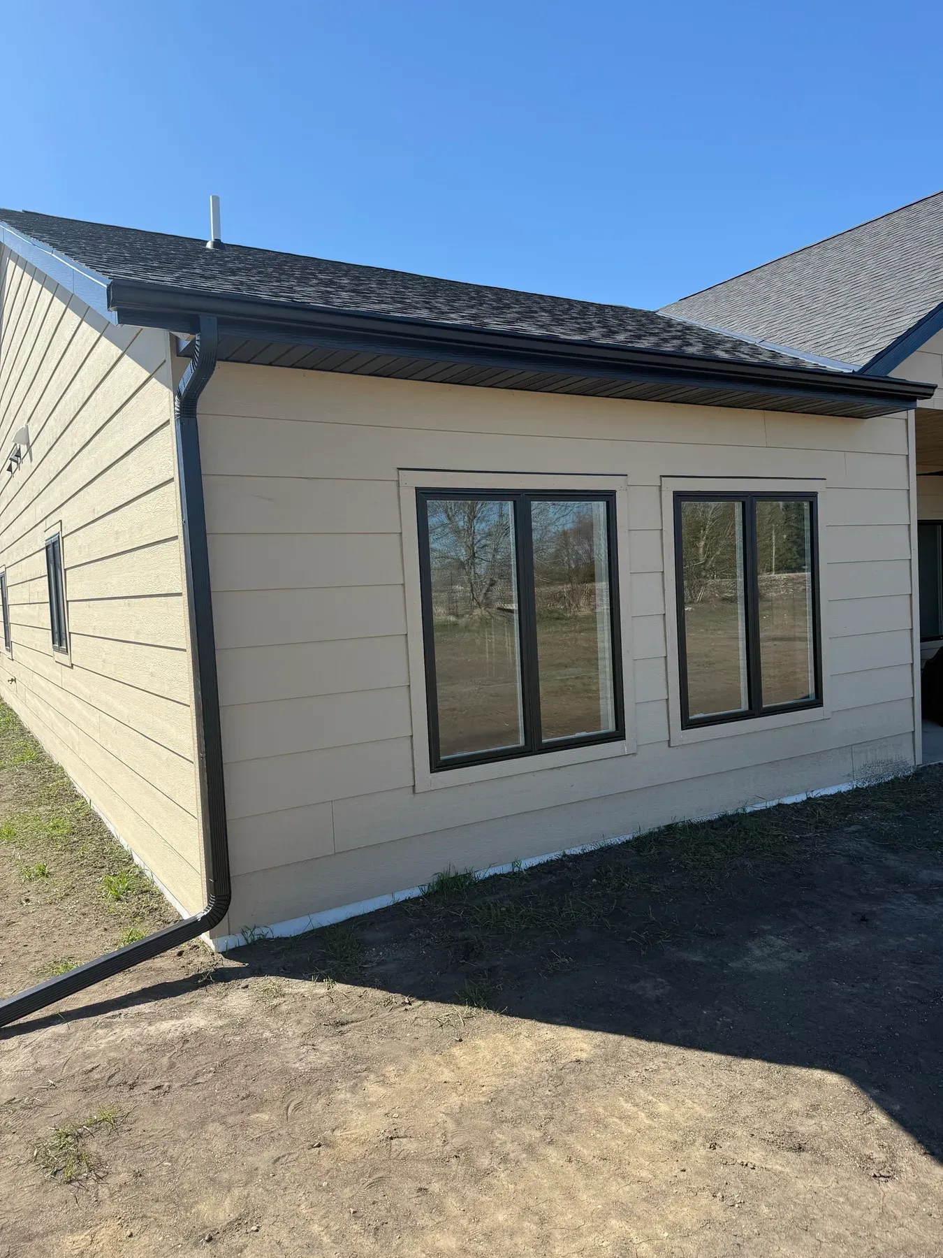 Finished downspout installed on a beige home