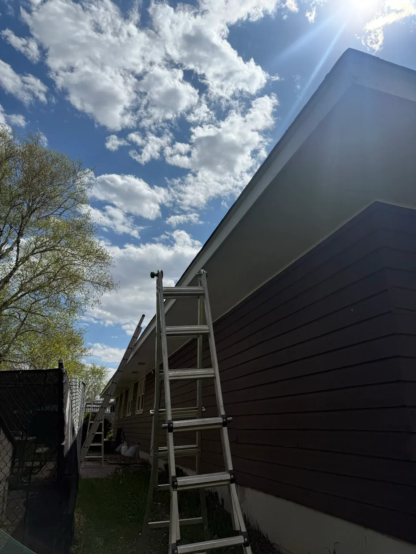 New gutter and downspout installed on a dark-sided home