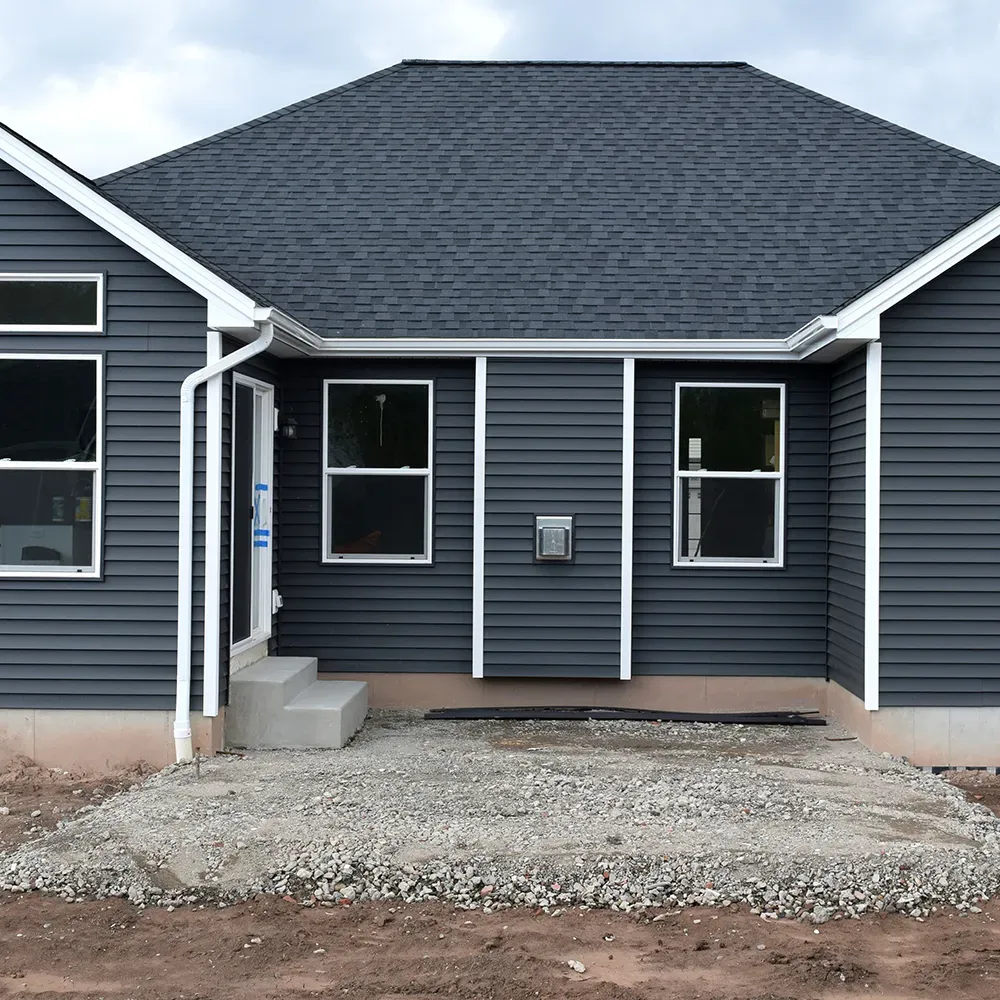 New white seamless gutters and downspouts on a charcoal-sided home
